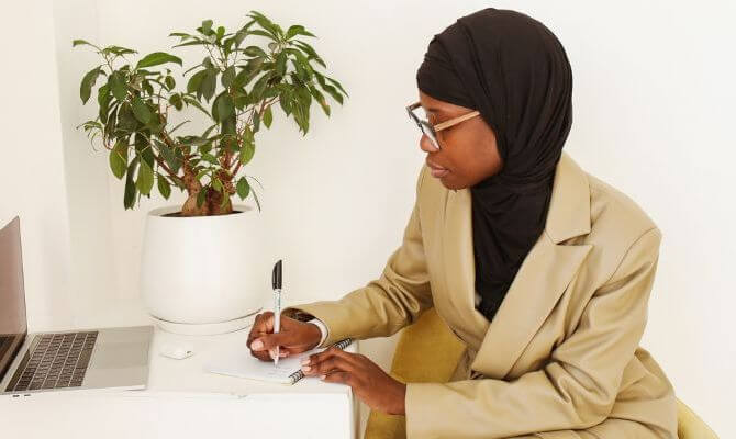 Woman in hijab writing SEO optimized content.